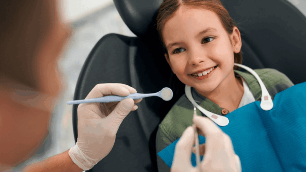 Child little patient sitting on a dental chair smiling on examination at a pediatric dentist.