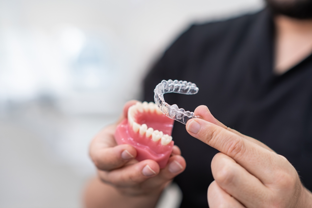 Doctor installing clear aligners on plastic lower human jaw model